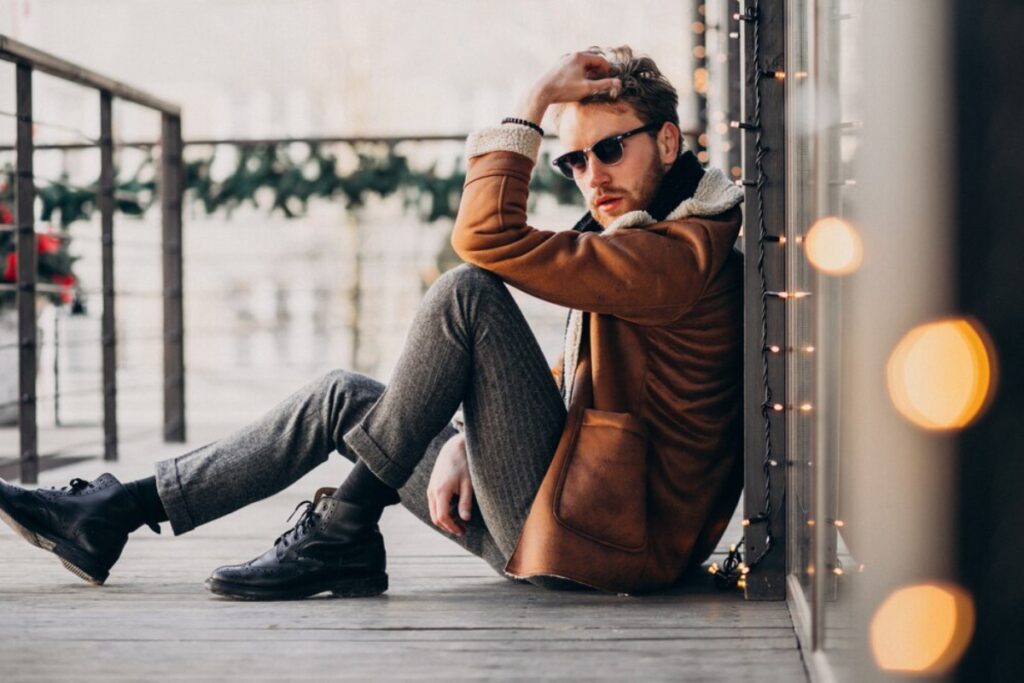 A man wearing sunglasses sits relaxed on a wooden deck, enjoying the outdoor atmosphere.